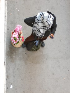 A woman in her headscarf with traditional shopping basic pausing to text from her cell phone
